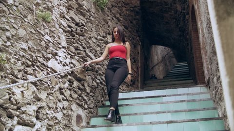 Attractive Italian woman walking down a flight of stairs in an alleyway. Wide shot on 8k helium RED camera.