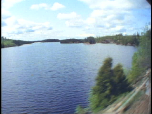 THE CANADIAN TRAIN, 1990, POV out train window, passing lake and pine trees