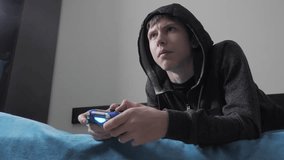 young teen and joystick man hooded sweater absorbed In online video lifestyle game. boy teenager in the hood playing video games on the console on the gamepad. Controller console gamepad. Gaming man