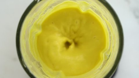 Tropical mango fruit with white coconut milk blended up into a healthy yellow smoothie, mango cocktail . The concept of a healthy lifestyle. Close up, slow motion, top view