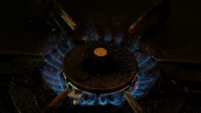 Blue fire on old dirty stove's burner in a dark kitchen. Panning to the right footage.