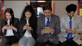 Business colleagues busy on their new technology smartphone mobile phones with touch screen for communication over internet and wifi using texting chat message and  video, addiction and habitual 