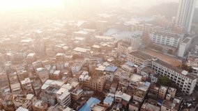 Aerial video shooting. Flying drone over typical Chinese area. In the frame of typical Chinese houses with dense buildings close. One can see warehouses. Dawn time in Guangzhou China.