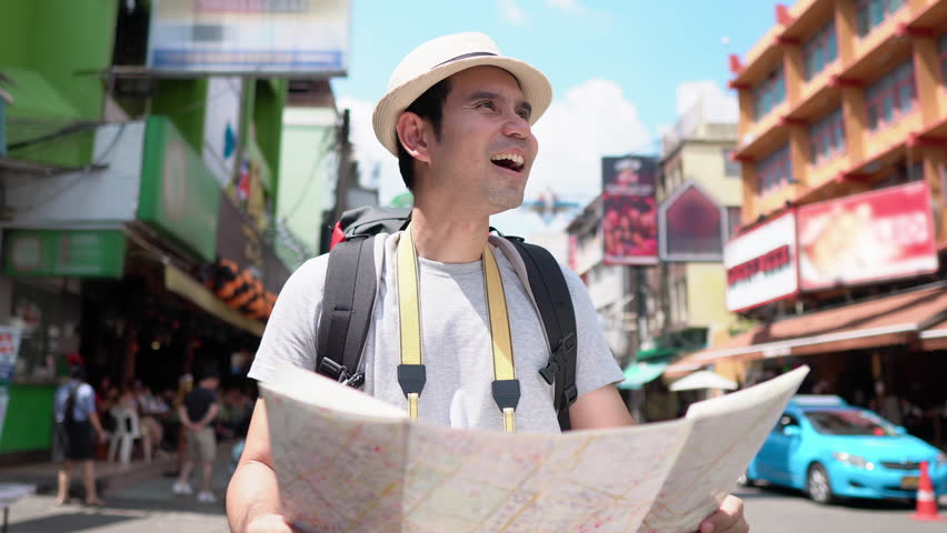 Asian tourist man looking at the map while solo traveling in Khao San road Bangkok, Thailand