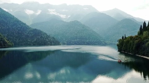 Mountain lake with turquoise water and green trees. Reflection in the water. Beautiful spring landscape with mountains, forest and lake. Aerial View. Drone shot over a beautiful mountain forest lake