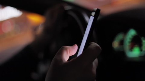 Texting with a smartphone in car at nigh