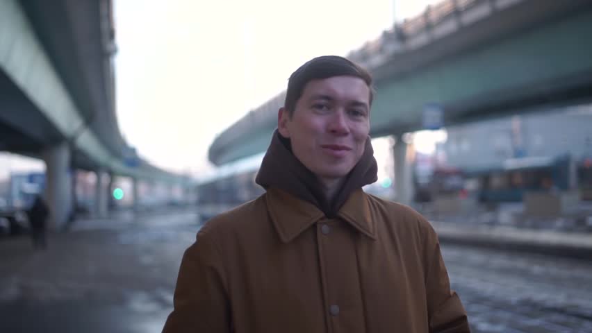 Close up of the Caucasian good looking man in winter clothes warming his shoulders with hands while standing outside in the on the cold winter day. Outside.
