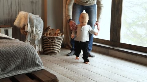 Baby taking first steps, child learning to walk. Slow motion