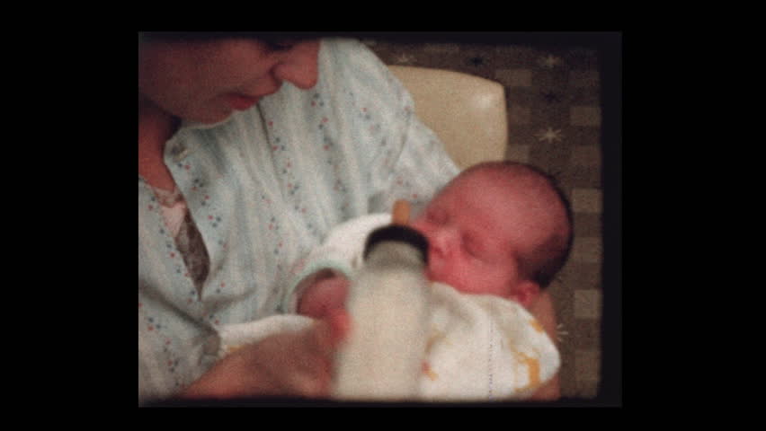 Mother holding newborn after feeding bottle 1959