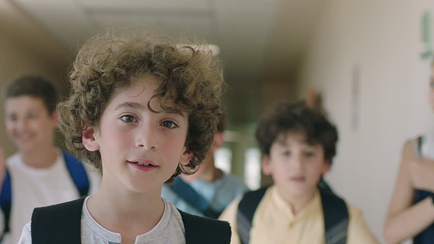 Close up portrait of beautiful , attractive , caucasian curly hair boy . Young boy looking and smiling on the camera inside school with friends . Portrait of children looks and smiles positive mood . Royalty-Free Stock Footage #1023585535