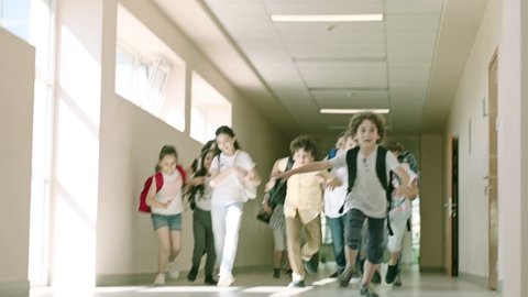 Children entering from school hallway to the classroom during recess, during school bell rings . Many Pupils Are Having Fun Before Lessons . Children running during bell ringing .