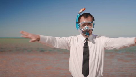  he businessman on the background of a beautiful sea in a mask and snorkel imitates swimming