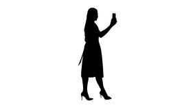 Silhouette Young woman in pink holding using smart phone recording video blog while walking.