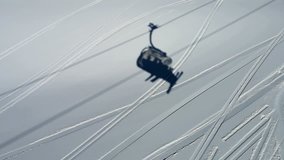 4k clip with skiers going up in a chair lift. Silhouette of the cable car is seen on the ski resort slopes.