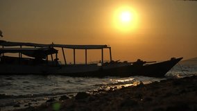 Beautiful video of sundown on beach, moored boat near shore, blurred light evening sun, shooting from ground