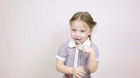 little girl shows how to brush her teeth on a white background