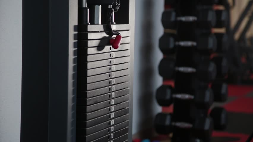 Handsome athletic man puts weight on the simulator.