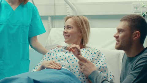 In the Hospital Midwife Gives Newborn Baby to a Mother to Hold, Supportive Father Lovingly Hugging Baby and Wife. Happy Family in the Modern Delivery Ward.