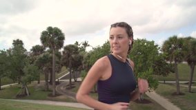 Slow motion of attractive fit young woman running in city park