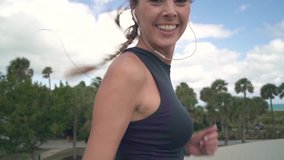 Slow motion of sporty smiling young woman running leading camera with arm