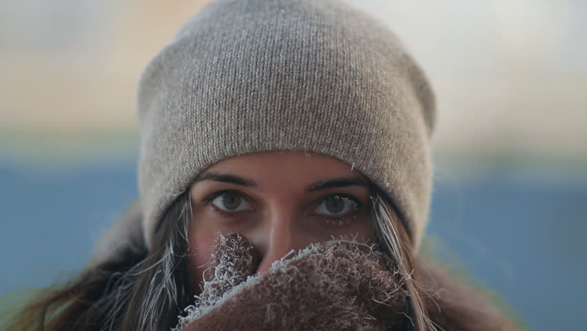 Portrait of a young charming woman covering her face with her hand from the cold.