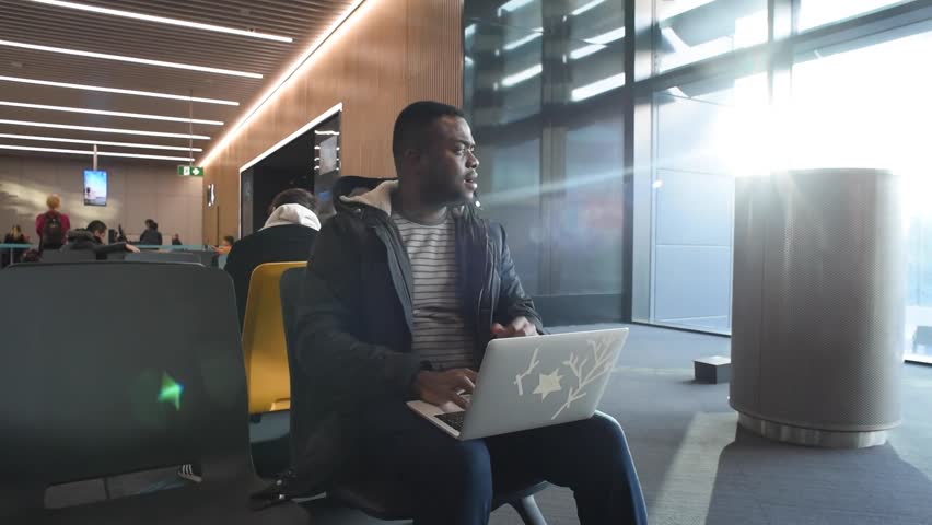 Black man waiting for his flight in terminal New Istanbul airport and using laptop. African american man working while waiting for landing to the plane. Shooting in January 2019 Turkey Istanbul  | Shutterstock HD Video #1023636409