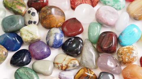 view of various tumbled gemstones rotating on white table close up