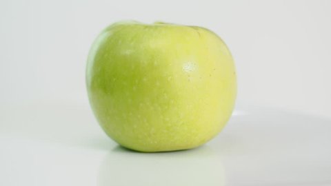 bitten yellow green apple on white plate rotates on white background, part 2