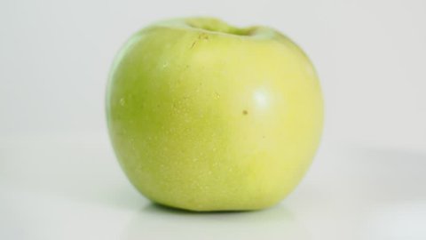 bitten yellow apple fruit on white plate rotates on white background