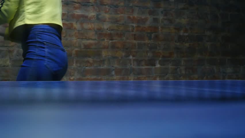 Young cute sporty woman playing in table tennis. Ping-pong net on foreground