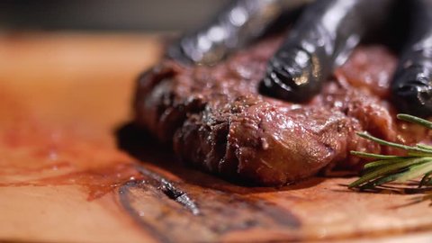 Hand in black gloves cutting meat steak with knife close up.