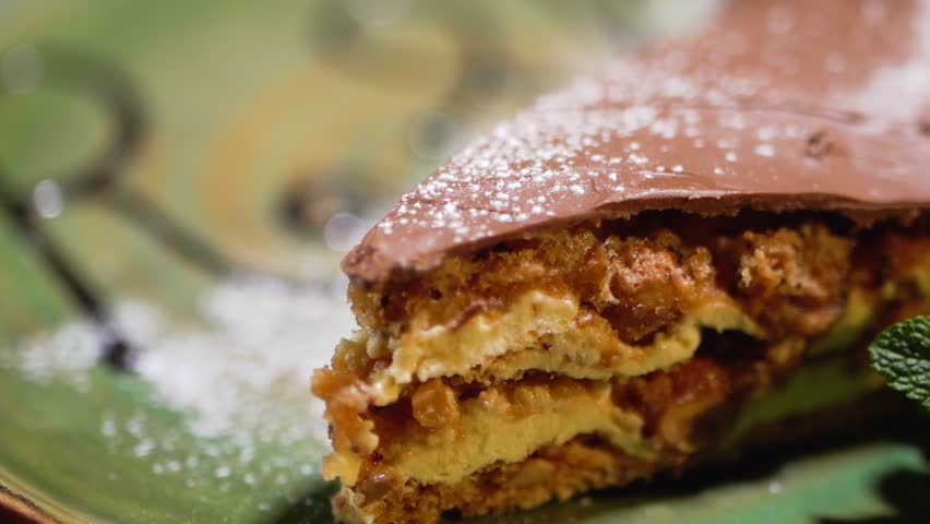 Tasty piece of caramel cake sprinkled with powdered sugar close up in modern restaurant