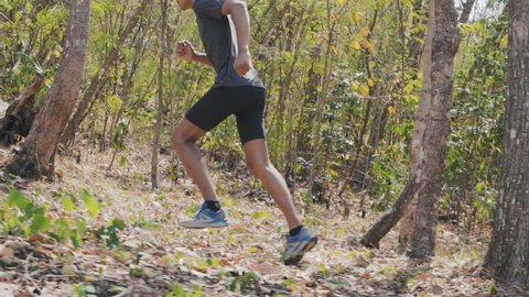 Young man running through the forest , trail running concept.