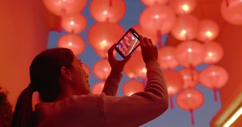 Woman take photo on cellphone under red lantern at night