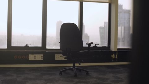 Camera moves away from a chair in an empty office  - vacant floor with no employees - abandoned office building - out of business or brand new unused office space with city view