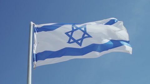 Shot of Israeli flag blowing in the wind in slow motion - State of Israel flag on pole with blue sky in background - Star of David
