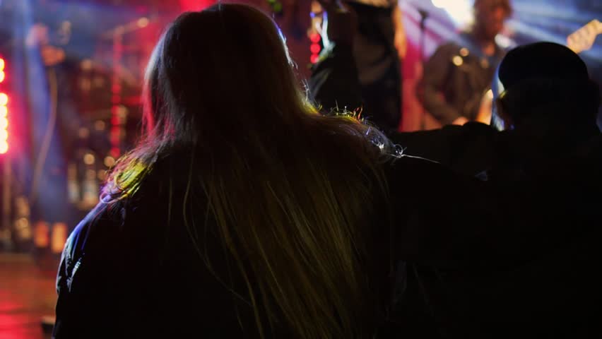 Rock concert in Germany. A fan with beautiful long hair dances at the stage of his favorite band.