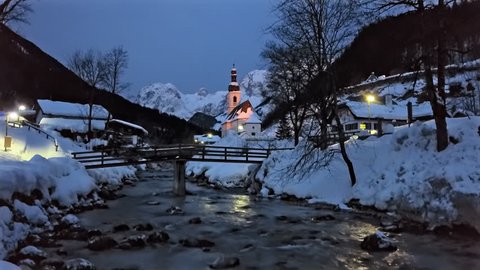 Winter morning flight over footbridge near famous Parish church St. Sebastian, in Ramsau, Berchtesgaden, Bavarian Alps Germany.