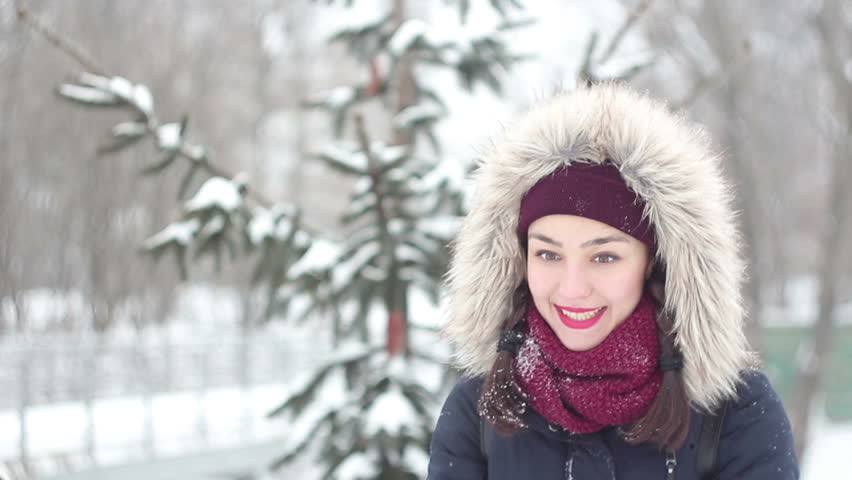 Beautiful young girl throws up snow with her hands and actively expressed joy, laughs and claps her hands.Portrait.