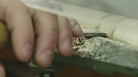 Craftsman in a process of woodworking on wood lathe machine, viewed in close-up on hands and tool - slow motion
