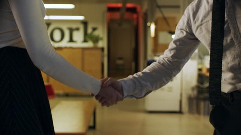Hiring, businessman in a dress shirt shaking hands with a woman colleague, a handshake in the office.