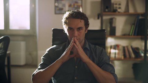 Medium to Close up shot on 8k helium RED camera.Ad agency creative director sitting in his chair thinking about his next big idea in his office with bright sunlight. 
