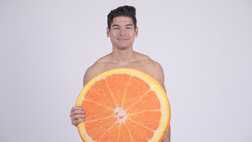 Happy young shirtless muscular man with orange pillow as healthy concept