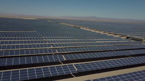 Aerial footage of hundreds solar energy modules or panels rows along the dry lands at Atacama Desert, Chile. Huge Photovoltaic PV Plant in the middle of the desert from an aerial drone point of view