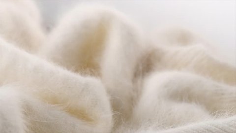 Wool background. Alpaca wool mohair clothes texture closeup. Natural Cashmere Soft and fluffy merino wool macro shot. Woolen fabric. Knitted hairy detail texture surface Rotated. 4K UHD video slowmo