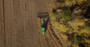 Farmer in tractor preparing land with seedbed cultivator. Agriculture. Tractor plowing field and preparing land for sowing. Spring or Autumn. Agronomy farming and husbandry concept. Aerial video.