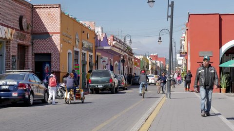 People walks in historical Mexican city center street, road Av. Miguel Hidalgo, Cholula, Puebla, Mexico, in January 15, 2019