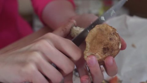 Woman cleans freshly picked forest porcino mushroom.
