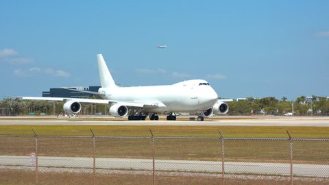 Generic Large Cargo Freighter Airplane with a White Unmarked Livery Ready for Departure Turning onto Airport Runway for Take-off on a Sunny Day