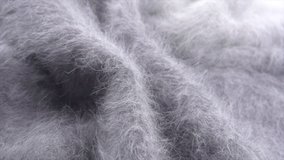 Wool background. Alpaca wool mohair clothes texture closeup. Cashmere Soft and fluffy grey merino wool macro shot. Woolen fabric. Knitted texture surface Rotated. Slow motion. 4K UHD video